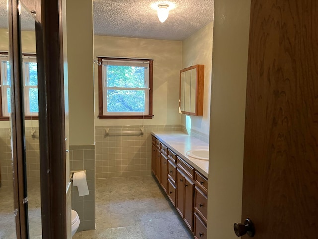 bathroom featuring tile walls, vanity, a textured ceiling, and toilet