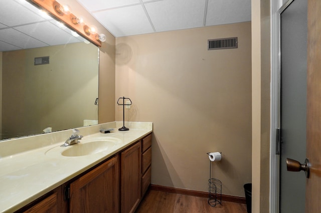 bathroom featuring vanity, hardwood / wood-style flooring, and a drop ceiling