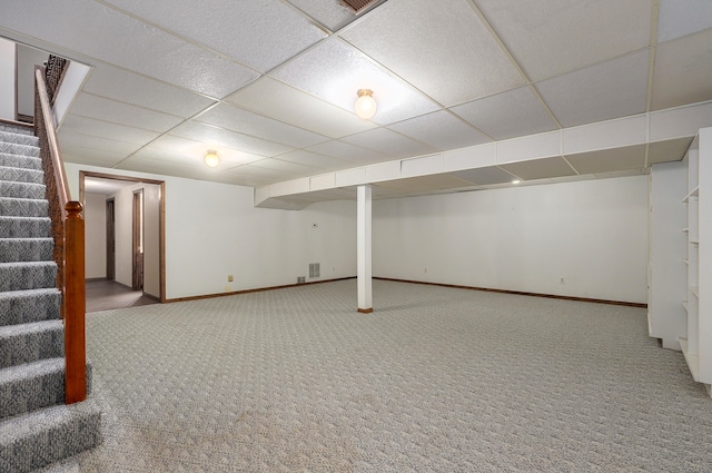 basement with a paneled ceiling and carpet