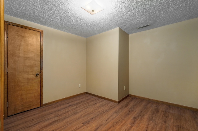 empty room with a textured ceiling and wood-type flooring