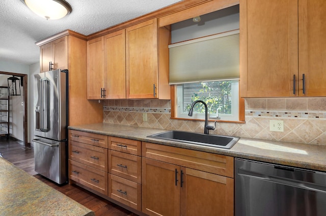 kitchen featuring appliances with stainless steel finishes, sink, backsplash, a textured ceiling, and dark wood-type flooring