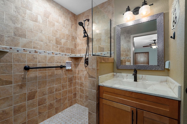 bathroom with vanity, ceiling fan, and tiled shower