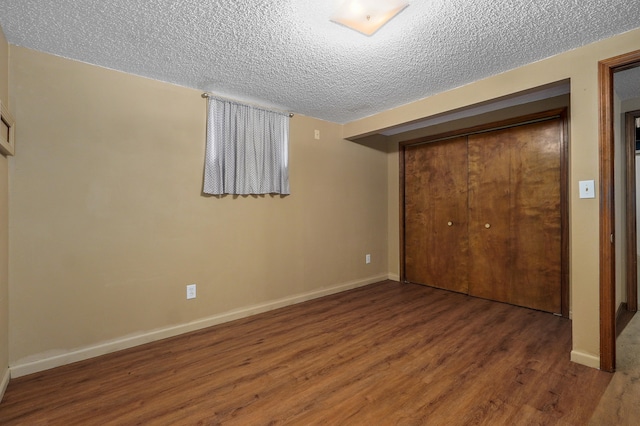 unfurnished bedroom with a textured ceiling, a closet, and dark hardwood / wood-style flooring