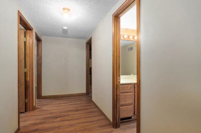 corridor with hardwood / wood-style floors and a textured ceiling