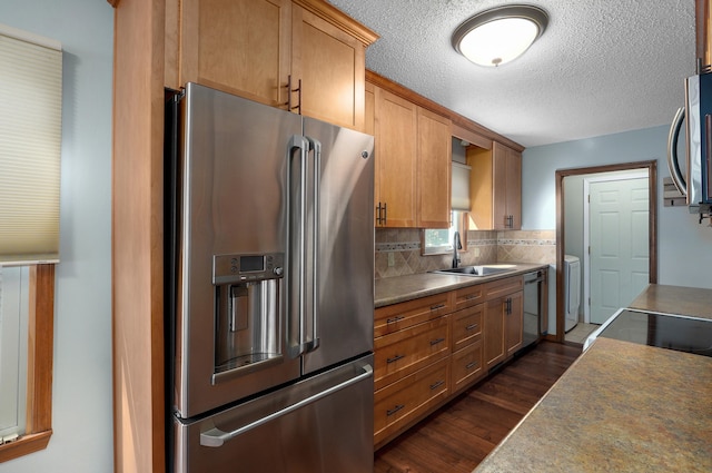 kitchen with dark hardwood / wood-style floors, washer / dryer, stainless steel appliances, backsplash, and sink