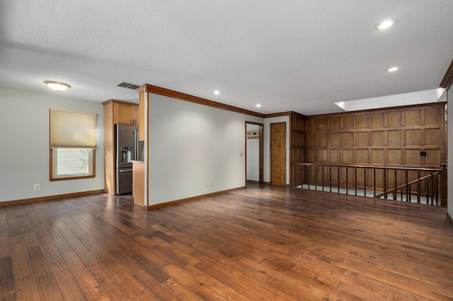 unfurnished room with a textured ceiling, crown molding, dark hardwood / wood-style floors, and a skylight