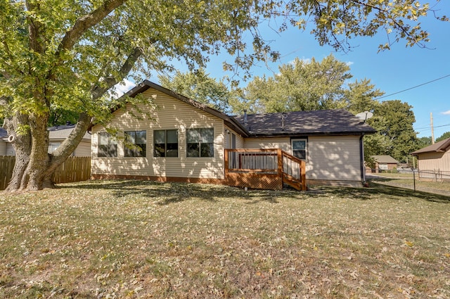 back of property with a deck and a lawn