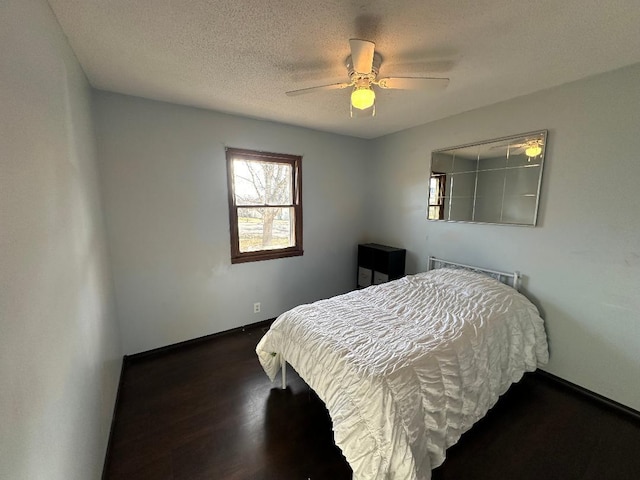 bedroom featuring ceiling fan, dark hardwood / wood-style floors, and a textured ceiling