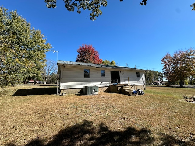 rear view of property featuring a yard and central air condition unit