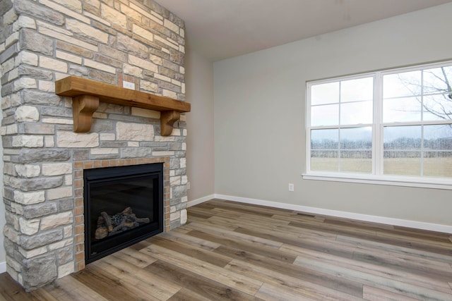 unfurnished living room with light hardwood / wood-style floors and a stone fireplace