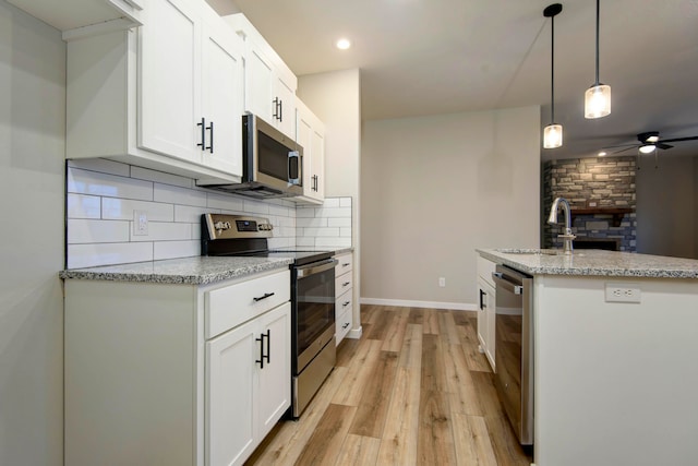 kitchen featuring white cabinetry, sink, pendant lighting, appliances with stainless steel finishes, and light wood-type flooring