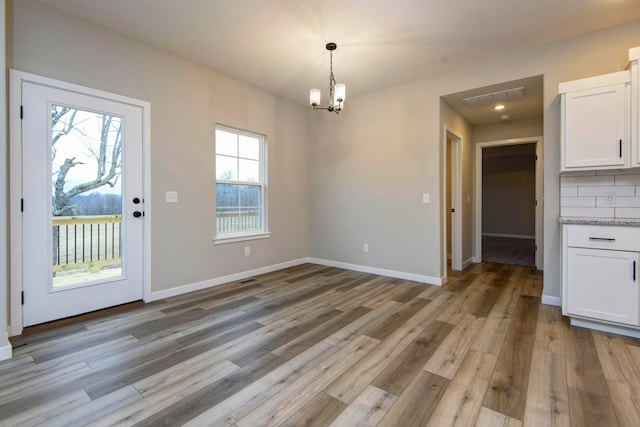 unfurnished dining area featuring a chandelier and hardwood / wood-style flooring