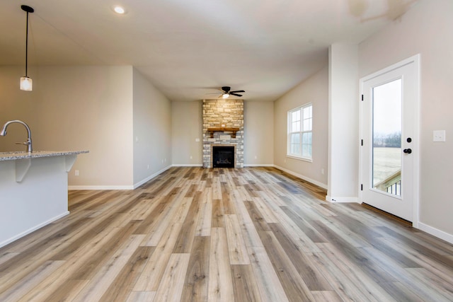 unfurnished living room with a fireplace, hardwood / wood-style floors, ceiling fan, and sink