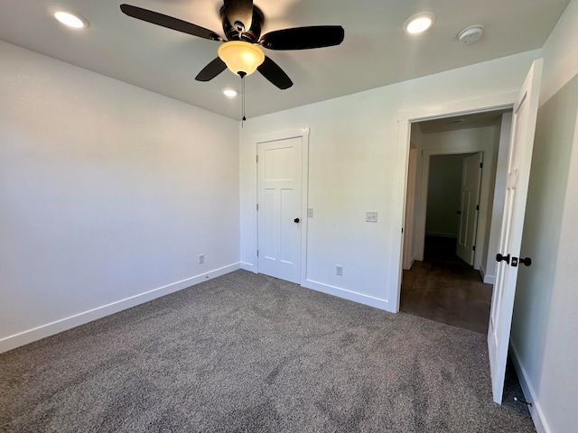 unfurnished bedroom with dark carpet, a closet, and ceiling fan