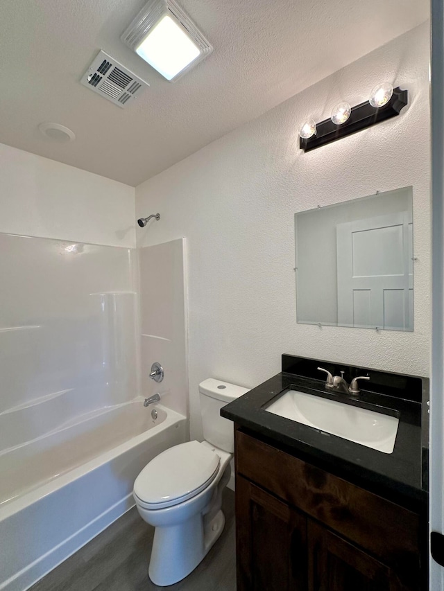 full bathroom with a textured ceiling, hardwood / wood-style flooring, toilet, shower / bathtub combination, and vanity