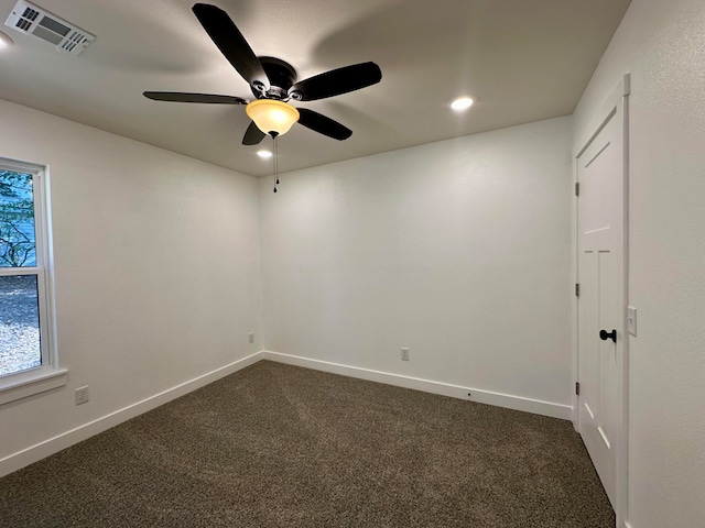 spare room featuring ceiling fan and dark colored carpet