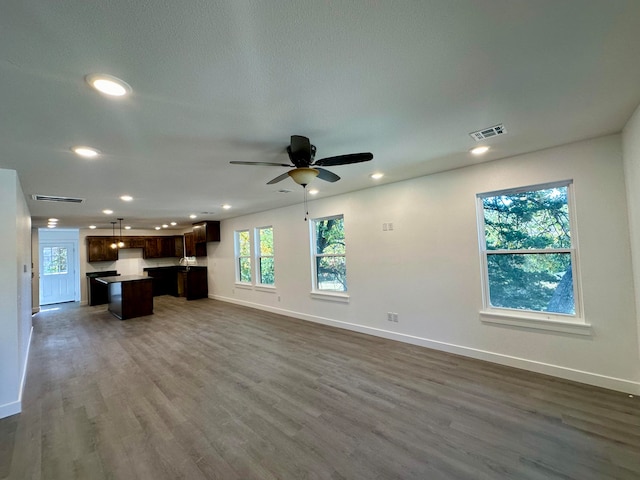 unfurnished living room with dark hardwood / wood-style floors and ceiling fan