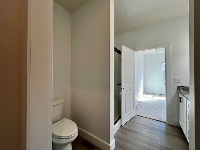 bathroom featuring vanity, toilet, hardwood / wood-style flooring, and an enclosed shower