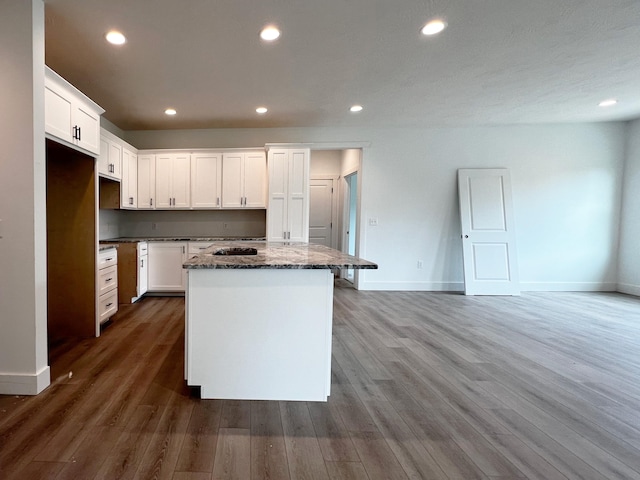 kitchen with white cabinetry, a kitchen island, and hardwood / wood-style floors