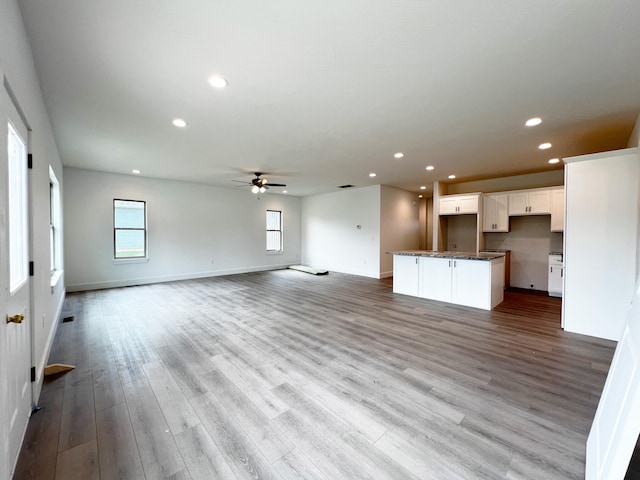 unfurnished living room with light wood-type flooring and ceiling fan