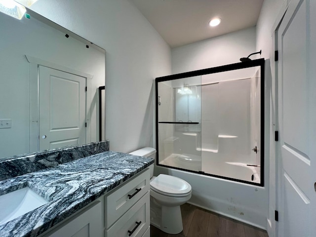 full bathroom featuring vanity, combined bath / shower with glass door, hardwood / wood-style flooring, and toilet