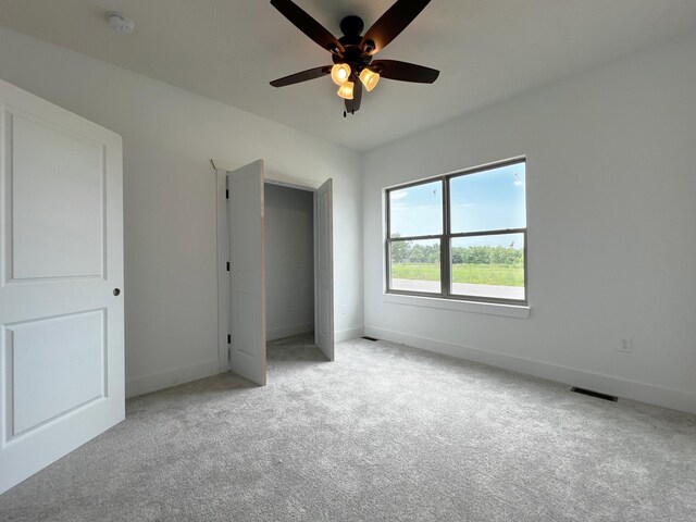 unfurnished bedroom featuring light colored carpet, a closet, and ceiling fan