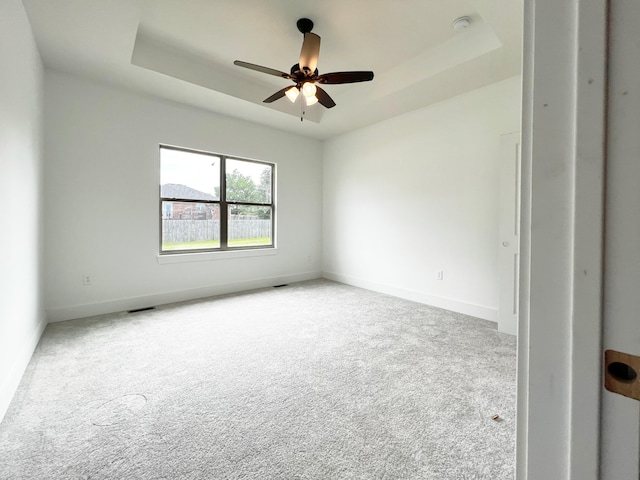 spare room featuring ceiling fan, carpet, and a raised ceiling