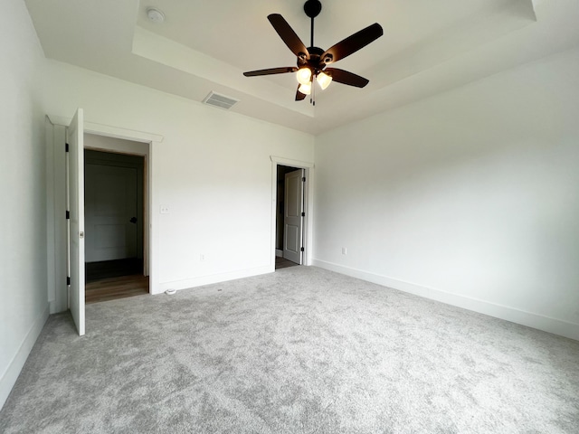 unfurnished bedroom featuring carpet, a raised ceiling, and ceiling fan