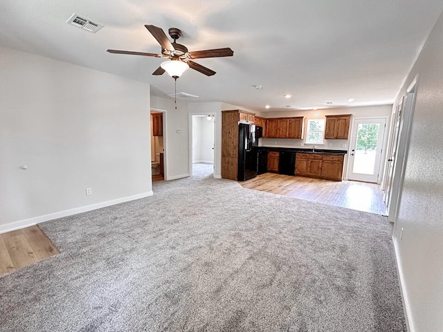 unfurnished living room featuring ceiling fan and light carpet