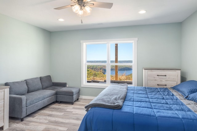 bedroom with ceiling fan, a water view, and light hardwood / wood-style floors