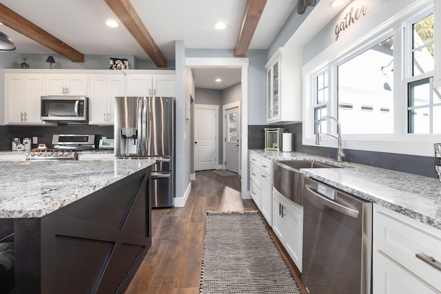 kitchen featuring beam ceiling, white cabinetry, and stainless steel appliances