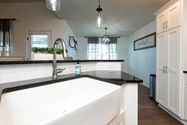 kitchen featuring sink, dark hardwood / wood-style flooring, pendant lighting, white cabinets, and a chandelier