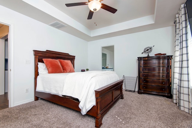 bedroom with a raised ceiling, light carpet, and ceiling fan