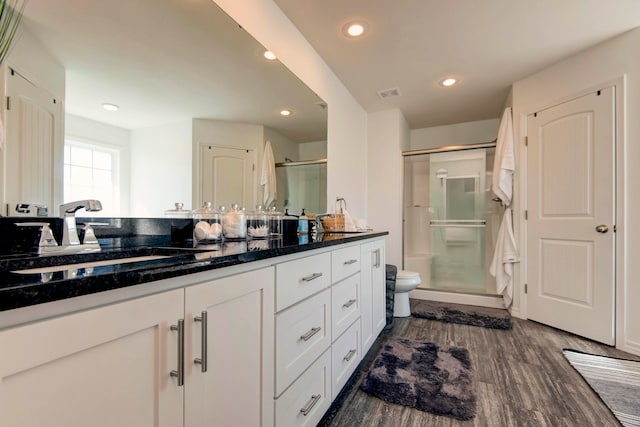 bathroom featuring toilet, hardwood / wood-style floors, a shower with shower door, and vanity