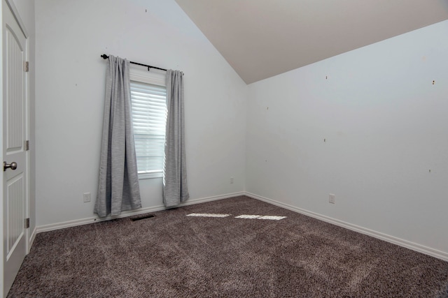 empty room featuring lofted ceiling and dark carpet