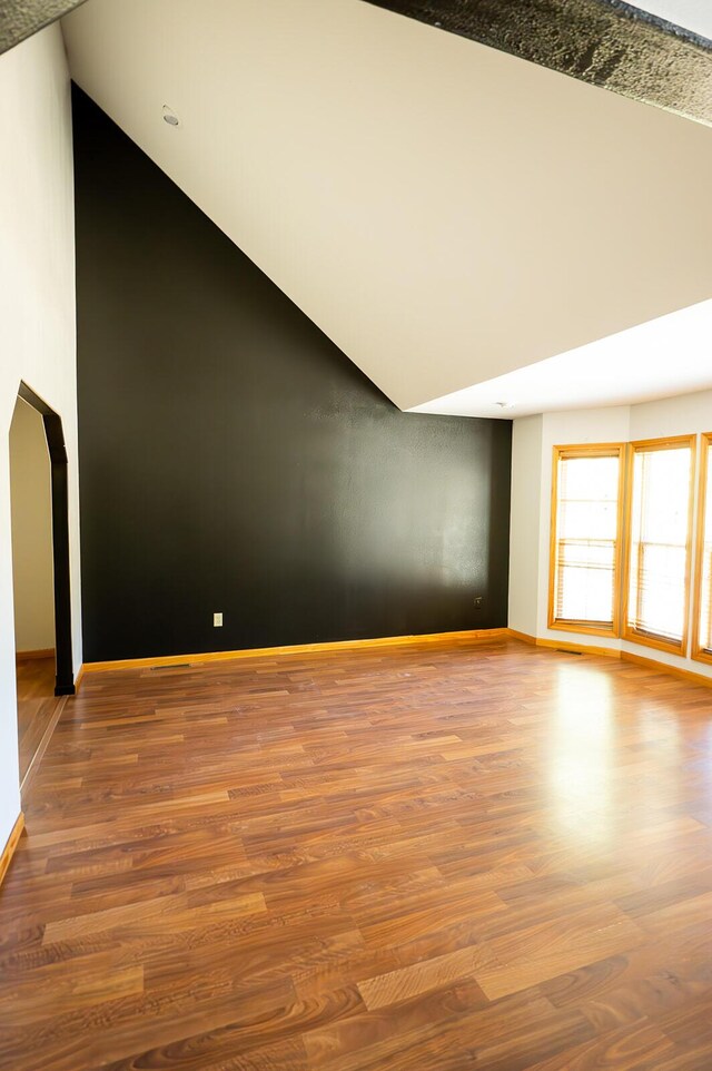 21620 County Road 232, Hermitage, MO 65668 - unfurnished living room featuring lofted ceiling, baseboards, wood finished floors, and arched walkways