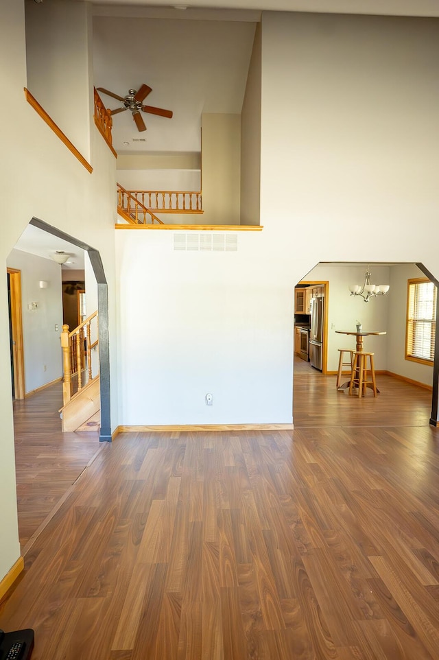 21620 County Road 232, Hermitage, MO 65668 - unfurnished living room featuring ceiling fan with notable chandelier, wood finished floors, a towering ceiling, and arched walkways