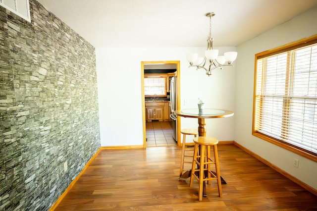 dining room featuring dark wood-type flooring, a healthy amount of sunlight, sink, and an inviting chandelier