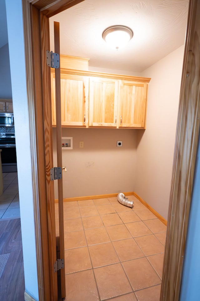 laundry room featuring hookup for a washing machine, light tile patterned floors, electric dryer hookup, and cabinets