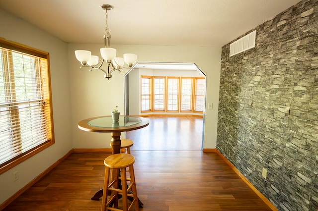 dining room with a notable chandelier, a healthy amount of sunlight, and dark hardwood / wood-style flooring