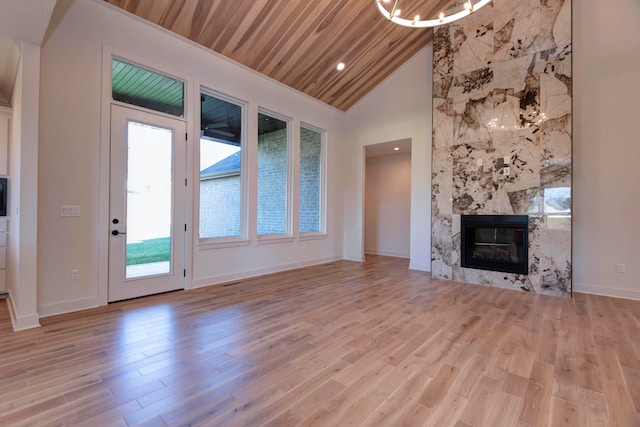 unfurnished living room with light hardwood / wood-style flooring, wood ceiling, a high end fireplace, and high vaulted ceiling