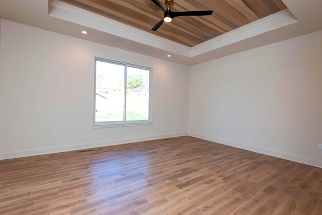 spare room with wood ceiling, a tray ceiling, light hardwood / wood-style floors, and ceiling fan