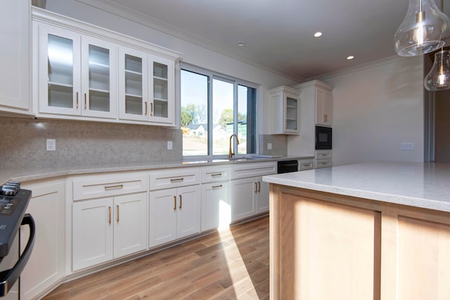 kitchen featuring white cabinetry, light stone countertops, ornamental molding, black appliances, and light hardwood / wood-style floors