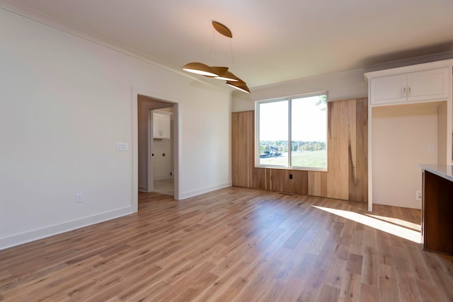 unfurnished living room featuring light hardwood / wood-style flooring and crown molding