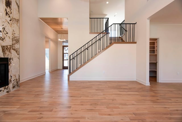 unfurnished living room with a premium fireplace, a high ceiling, and light wood-type flooring