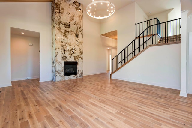 unfurnished living room featuring a premium fireplace, high vaulted ceiling, and light wood-type flooring