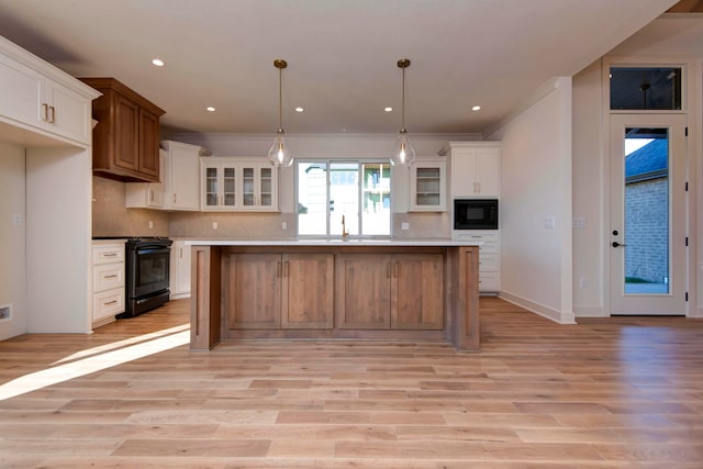 kitchen with white cabinetry, black appliances, decorative light fixtures, and a kitchen island