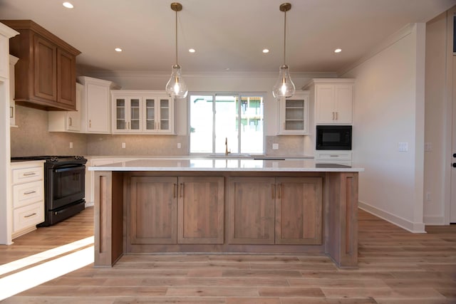 kitchen with black appliances, light wood-type flooring, a kitchen island, and white cabinets