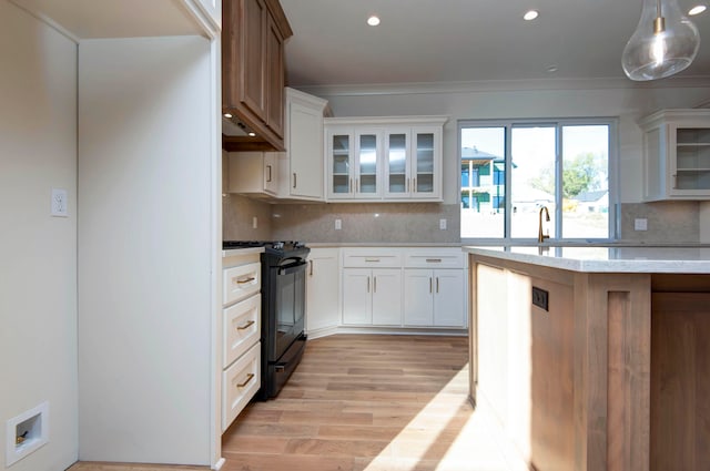 kitchen featuring light hardwood / wood-style flooring, decorative light fixtures, black stove, and white cabinets