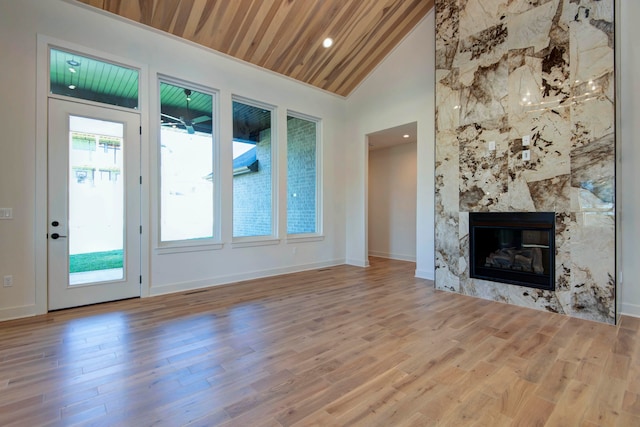 unfurnished living room featuring a premium fireplace, light wood-type flooring, and wooden ceiling